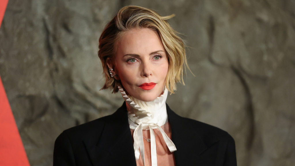 Charlize Theron Goes Topless Under Men’s Jacket for Apex Premiere